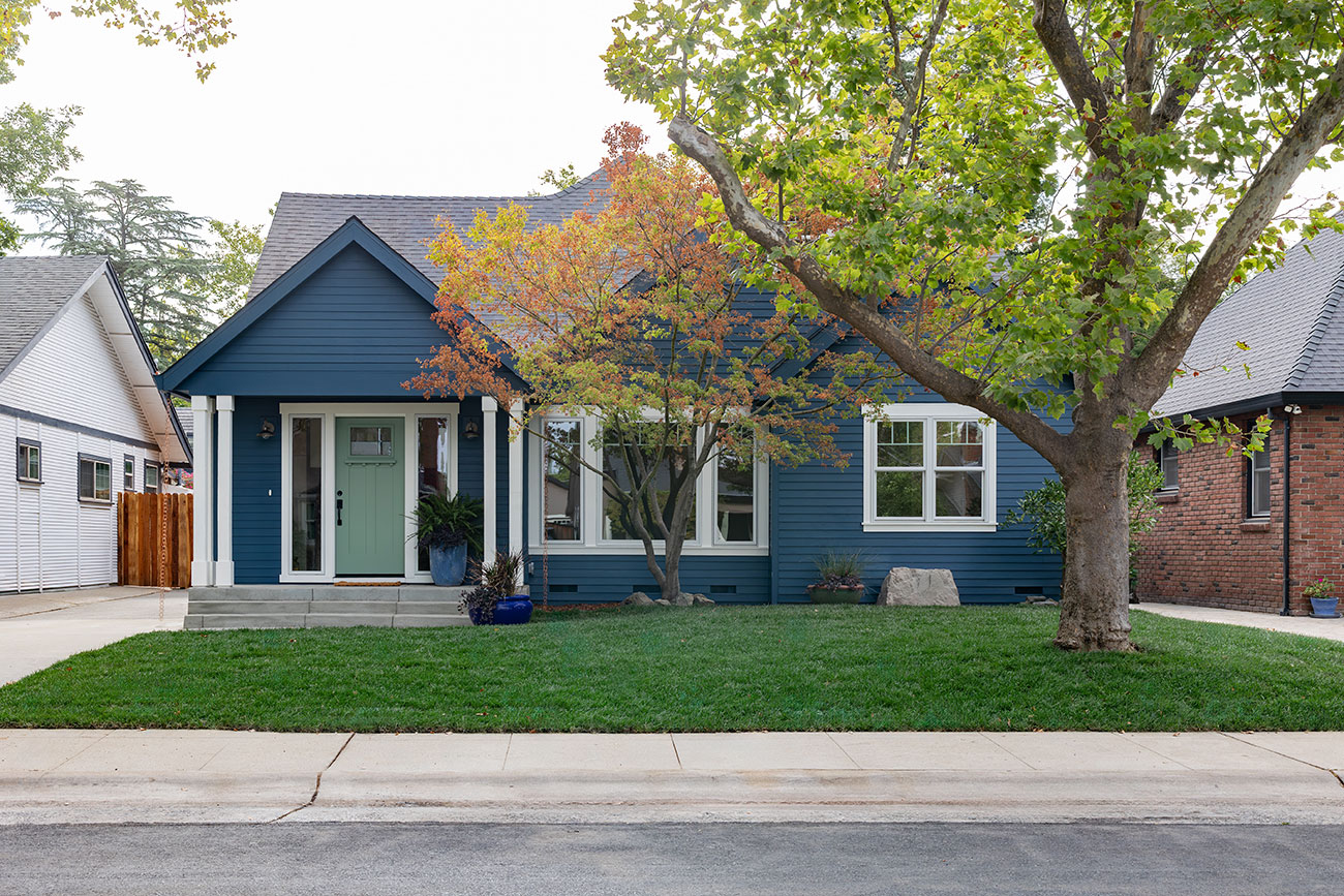 Blue Craftsman-style home with front porch and tree-lined yard